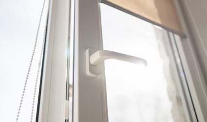 Roll Blinds on the windows, the sun does not penetrate the house. Modern white plastic pvc window with forest background at home, closeup view. Home interior
